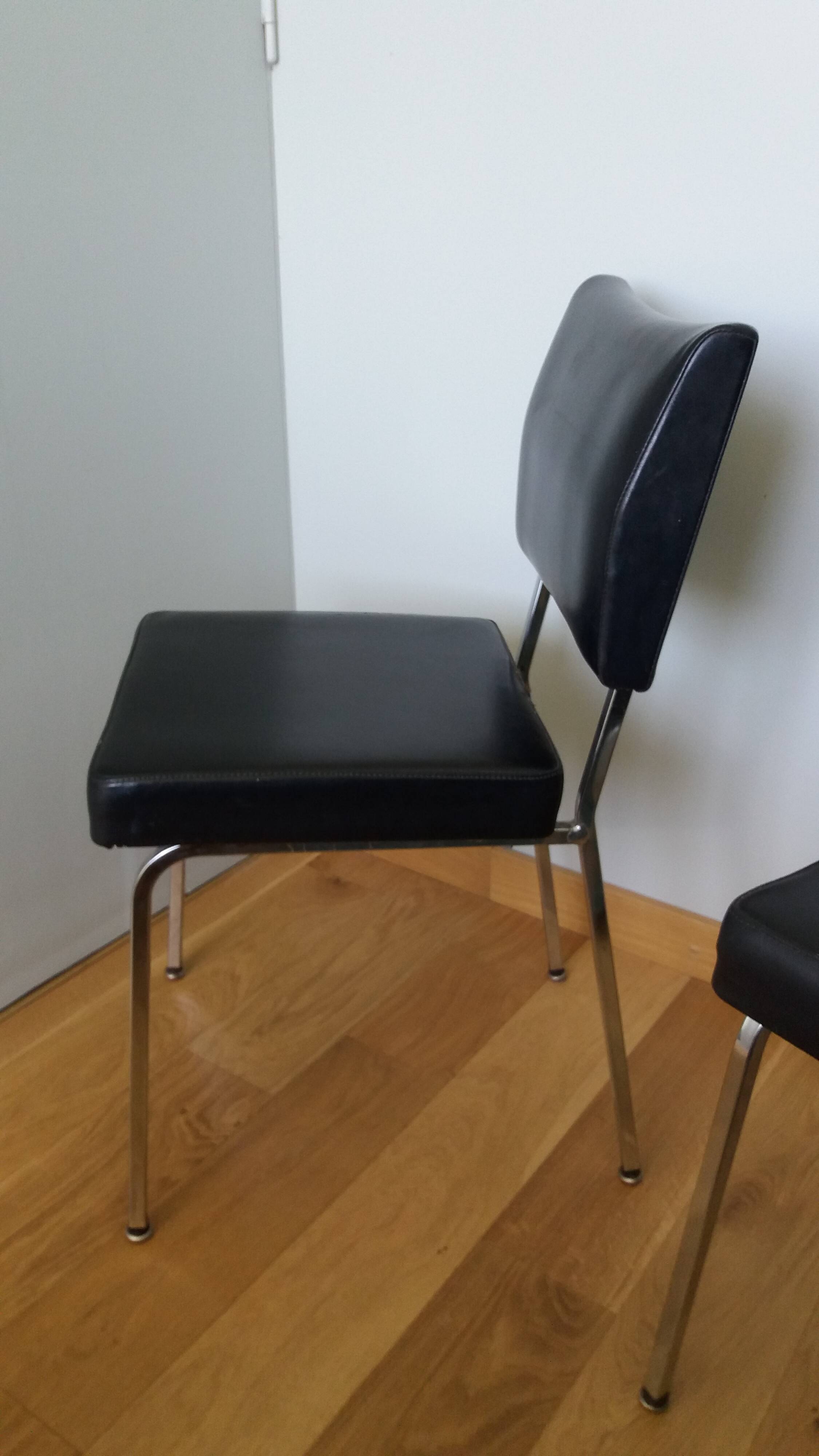 Chrome metal chairs and black faux leather upholstery in retro modernist style.