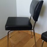 Chrome metal chairs and black faux leather upholstery in retro modernist style.