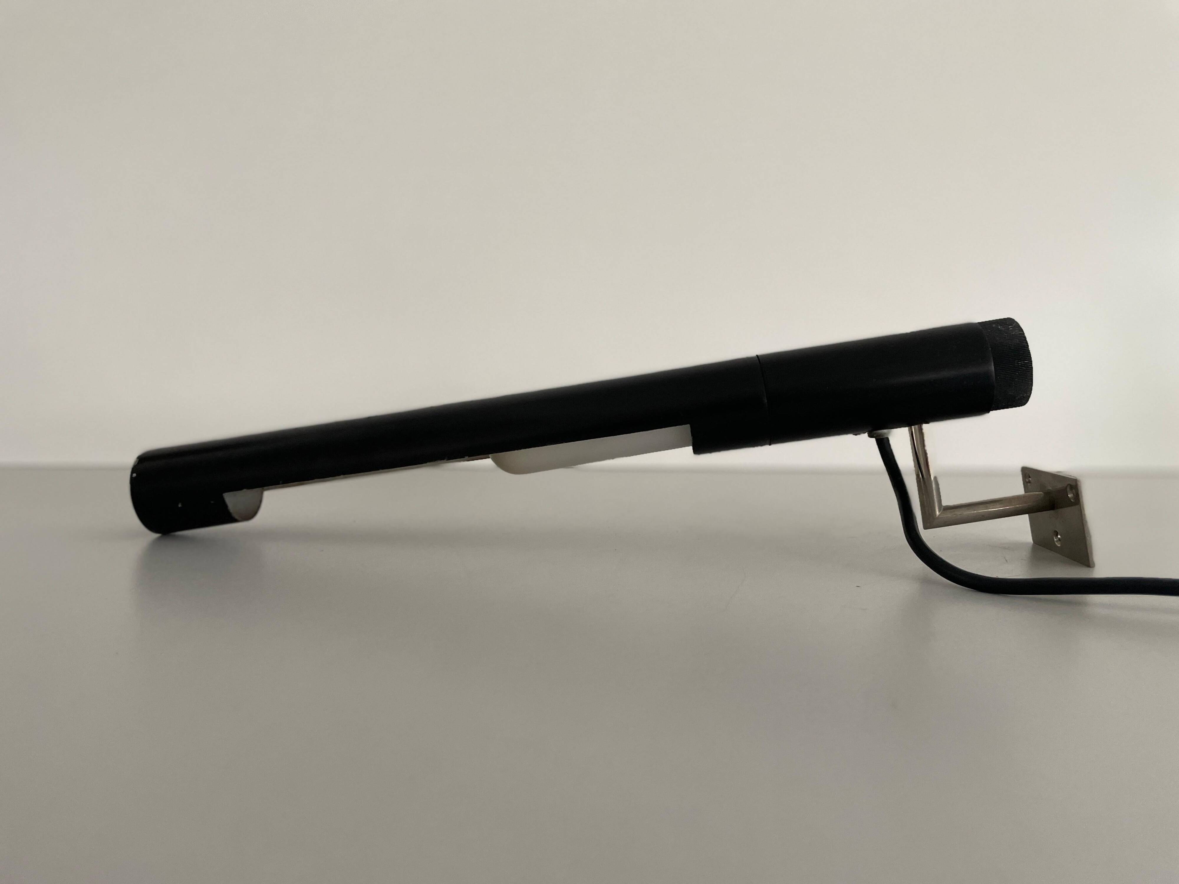 Minimalist black metal wall light with a cylindrical design, 1960s, Germany.