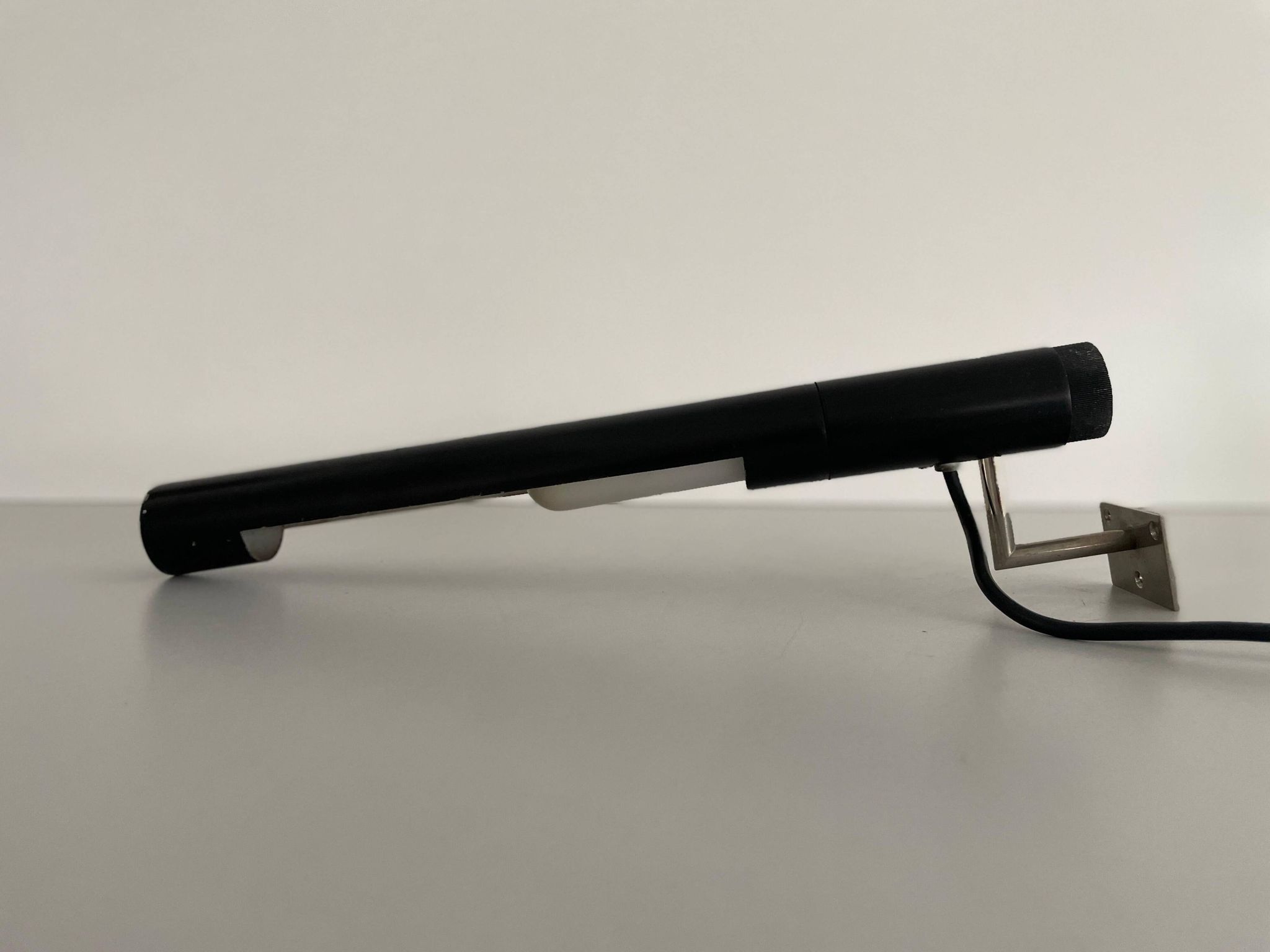 Minimalist black metal wall light with a cylindrical design, 1960s, Germany.