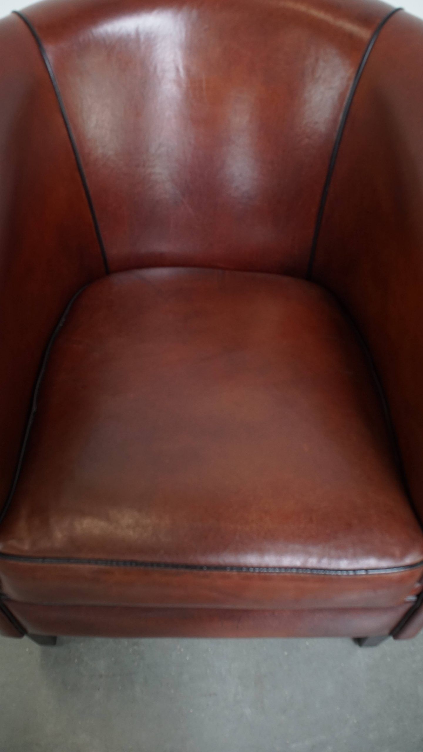 Sheepskin club armchair in a warm deep colour finished with black piping