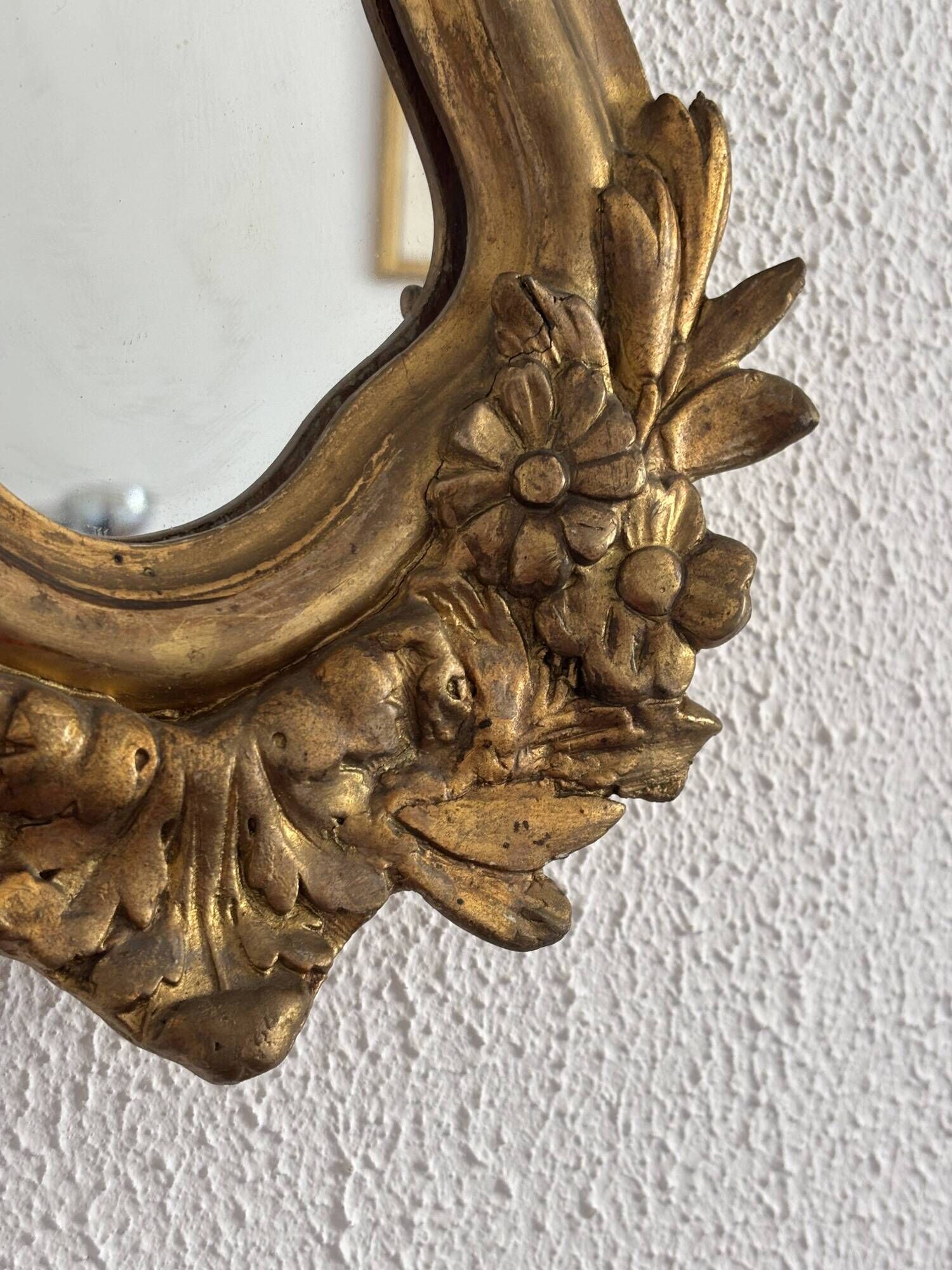 Antique rococo mirror with putti, gilded carved wood and stucco frame, 19th century.