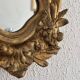 Antique rococo mirror with putti, gilded carved wood and stucco frame, 19th century.