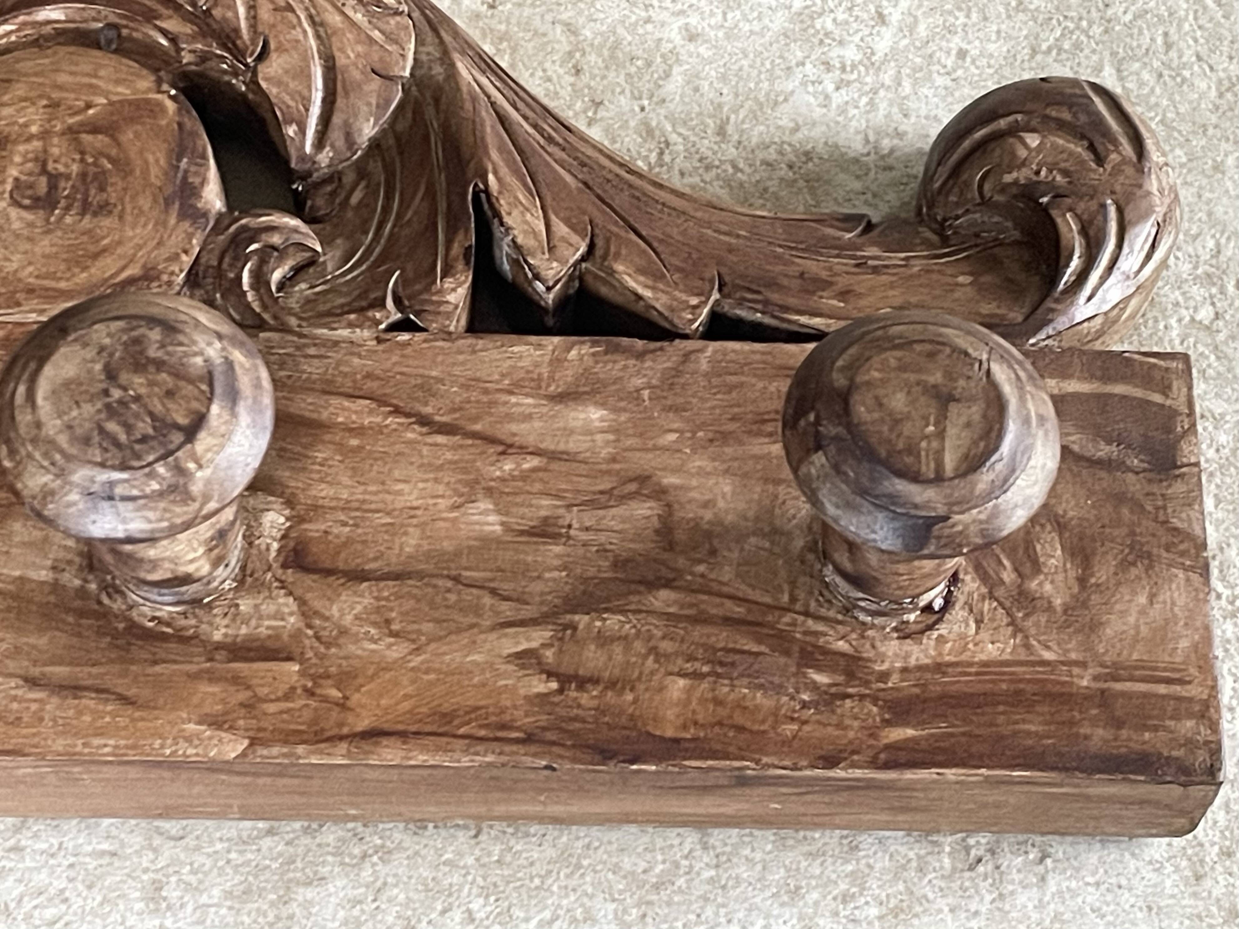 Wall-mounted coat rack on a carved wooden pediment