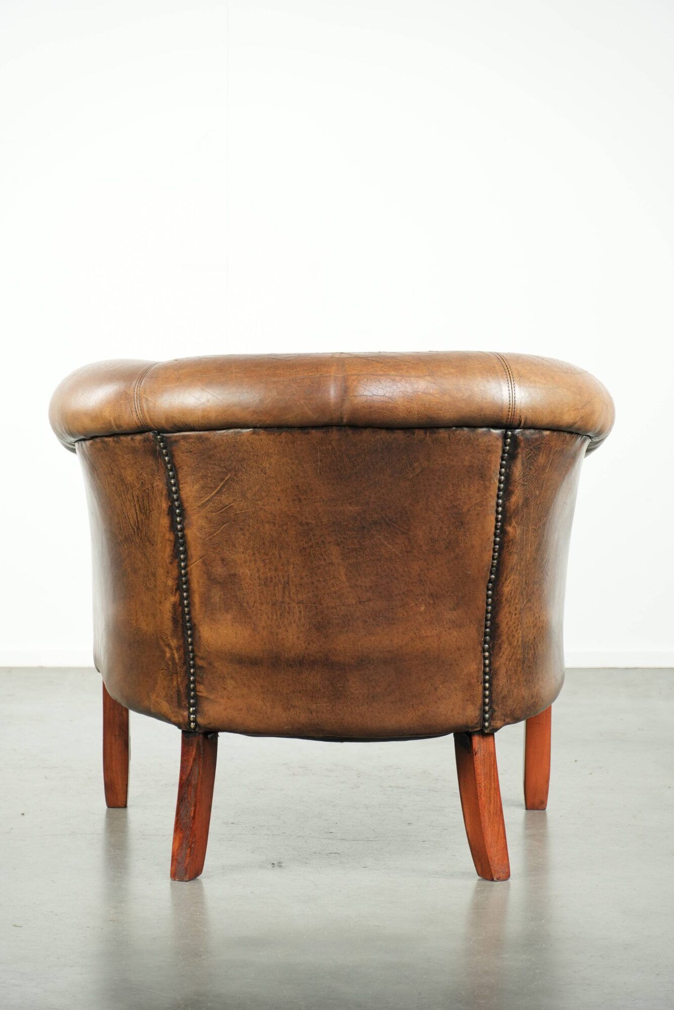 Sheepskin club armchair in a brown colour finished with decorative nails