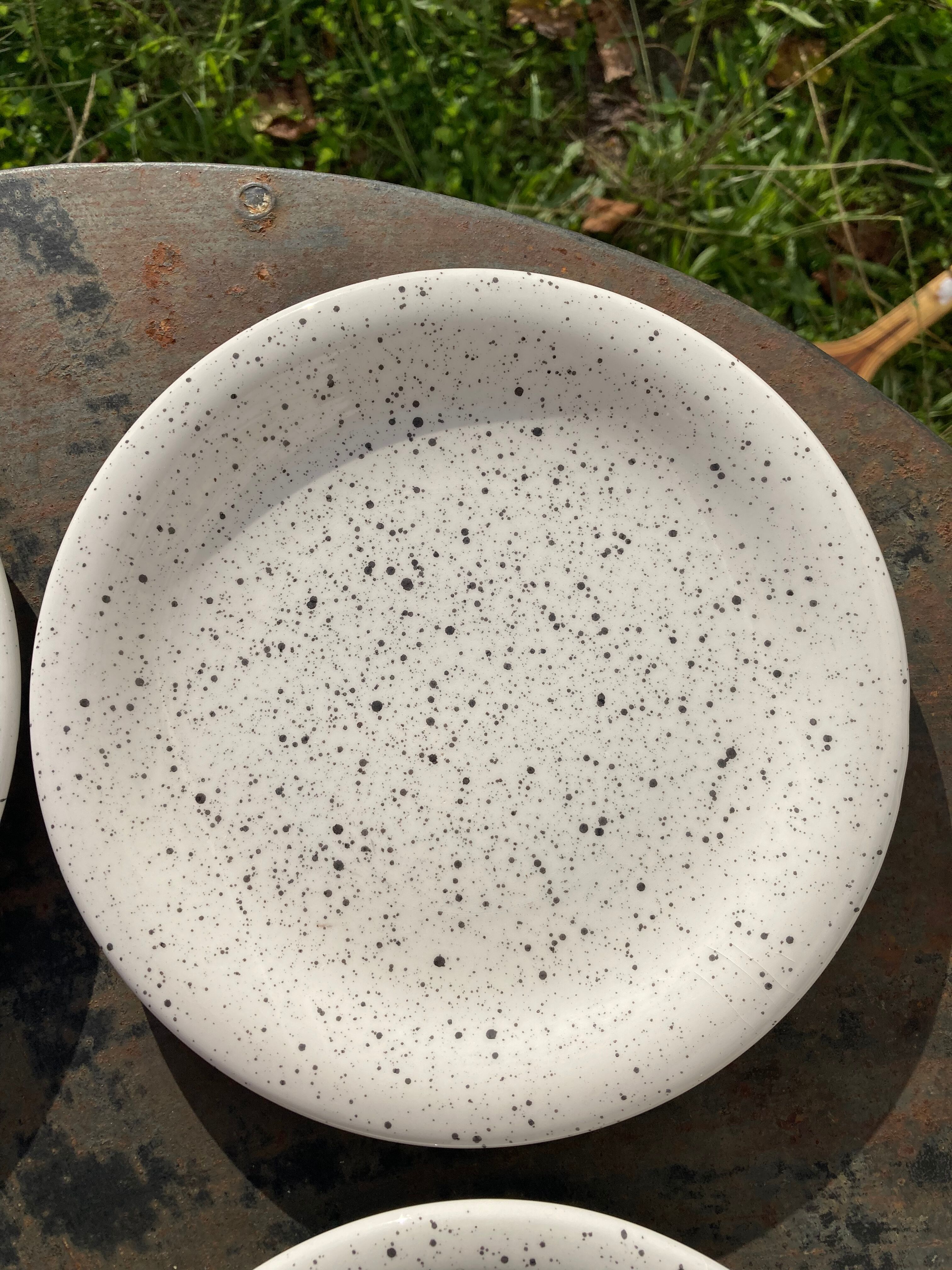 4 black speckled dessert plates on a vintage white background