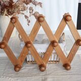 Antique wall-mounted coat rack accordion in dark pine, 10 wooden hooks.