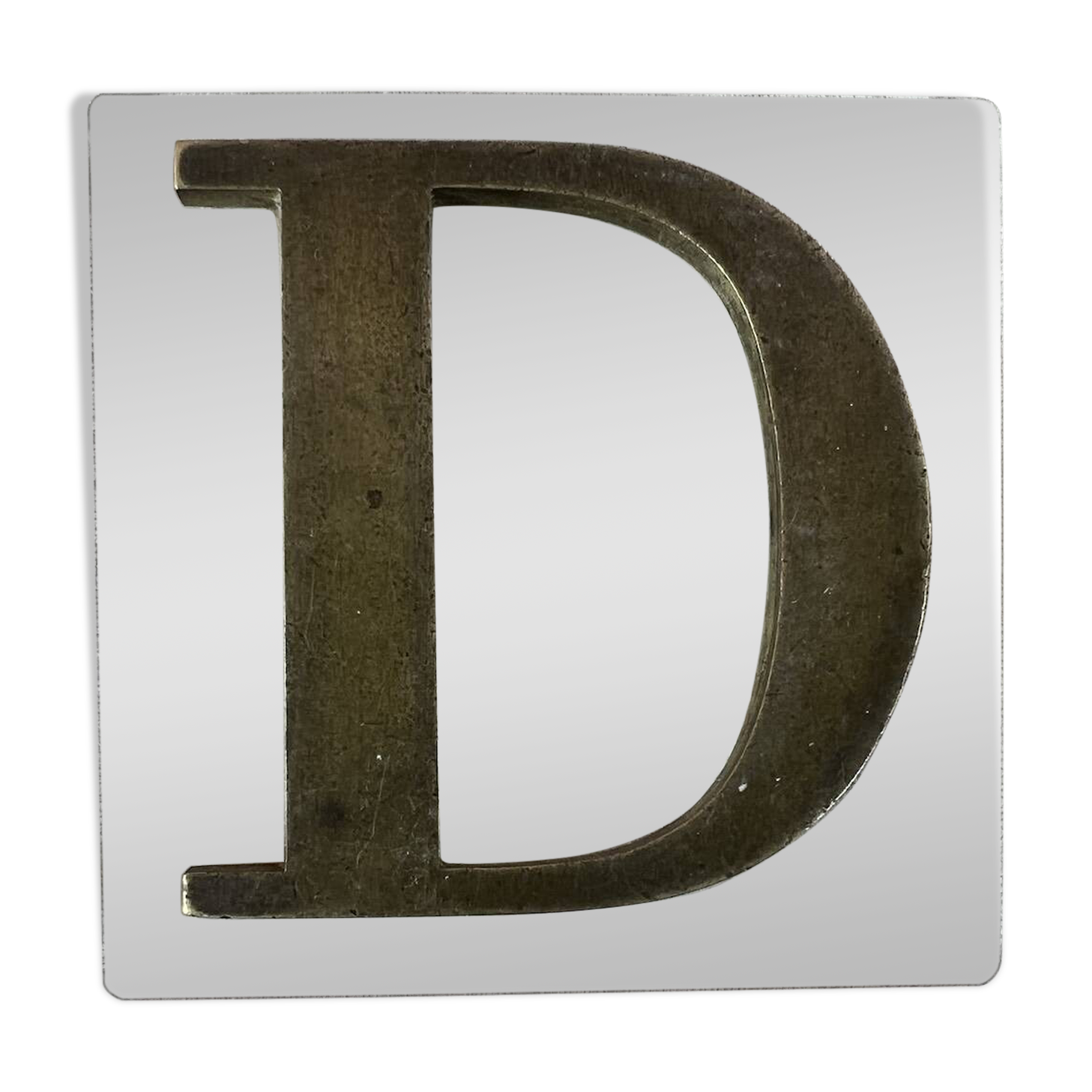 Metal letter D on glass plate