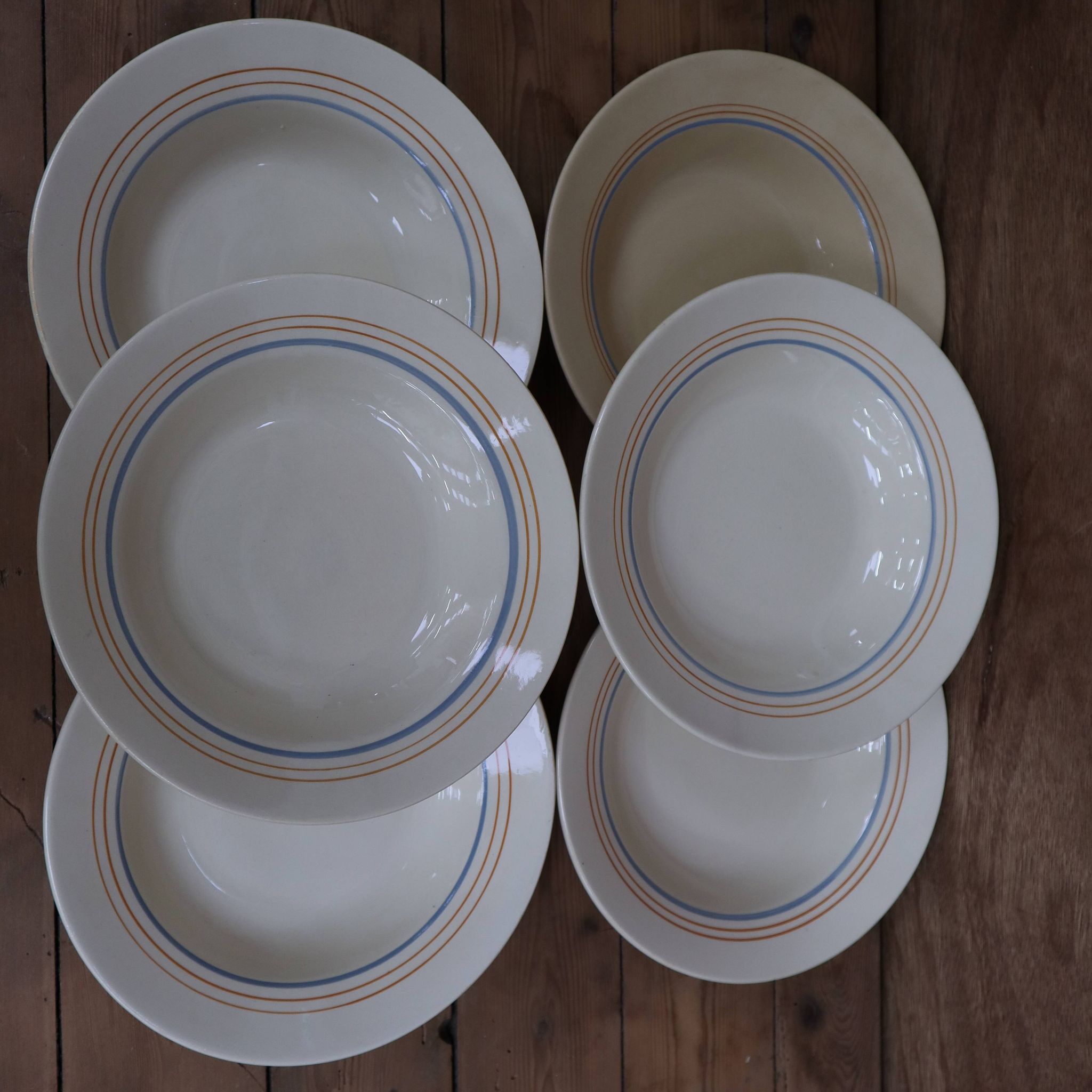 6 old cream-coloured deep plates with blue/orange trim.
