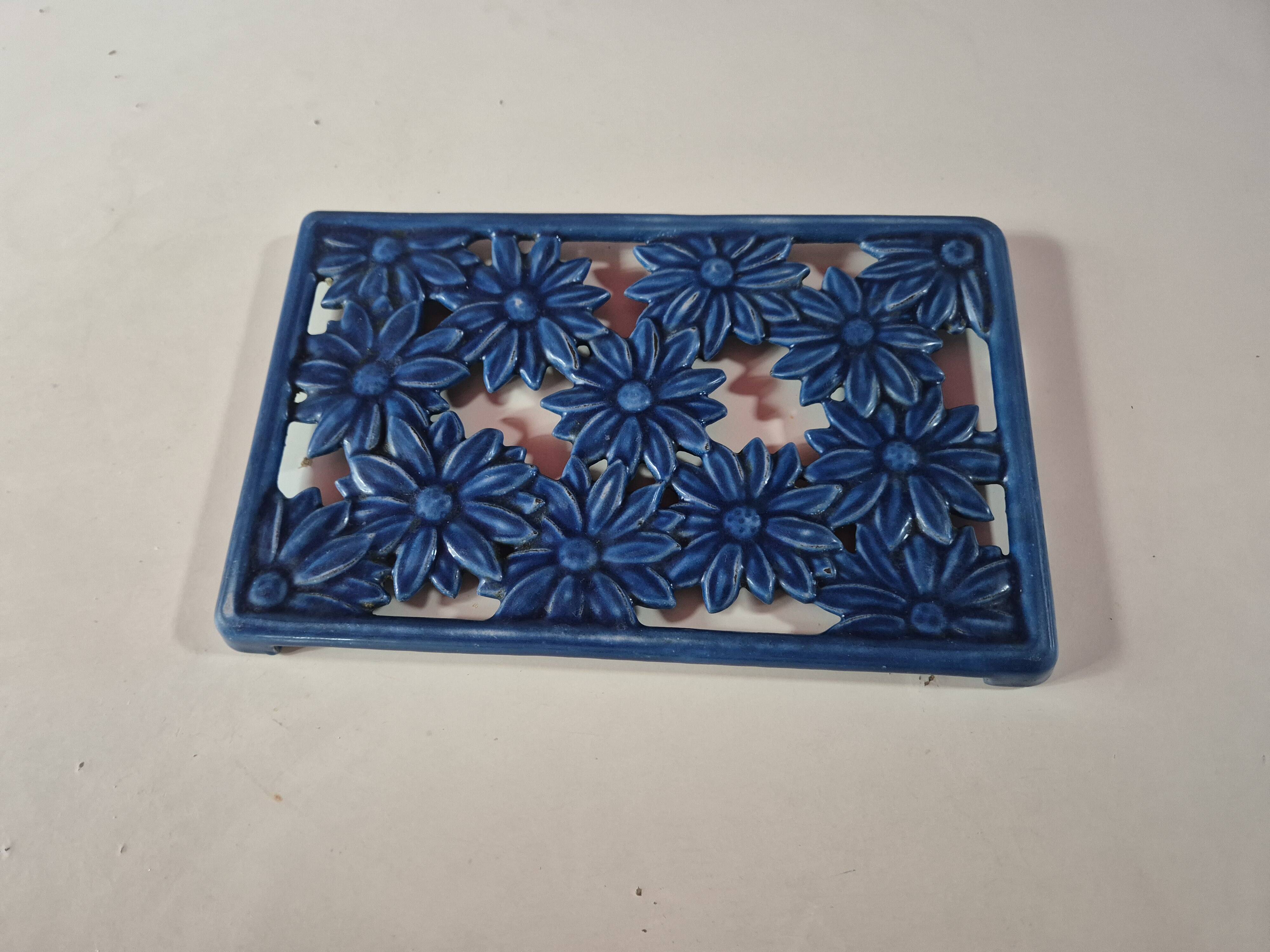 Blue cast iron trivet with flowers, small chip in the paint otherwise very good.