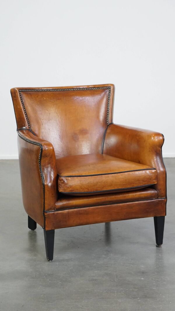 Fauteuil en peau de mouton couleur cognac avec passepoil noir et clous décoratifs