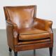 Cognac-colored sheepskin armchair with black piping and decorative nails