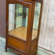 Louis XV style display cabinet in cherry wood with a mirrored back and glass shelves.