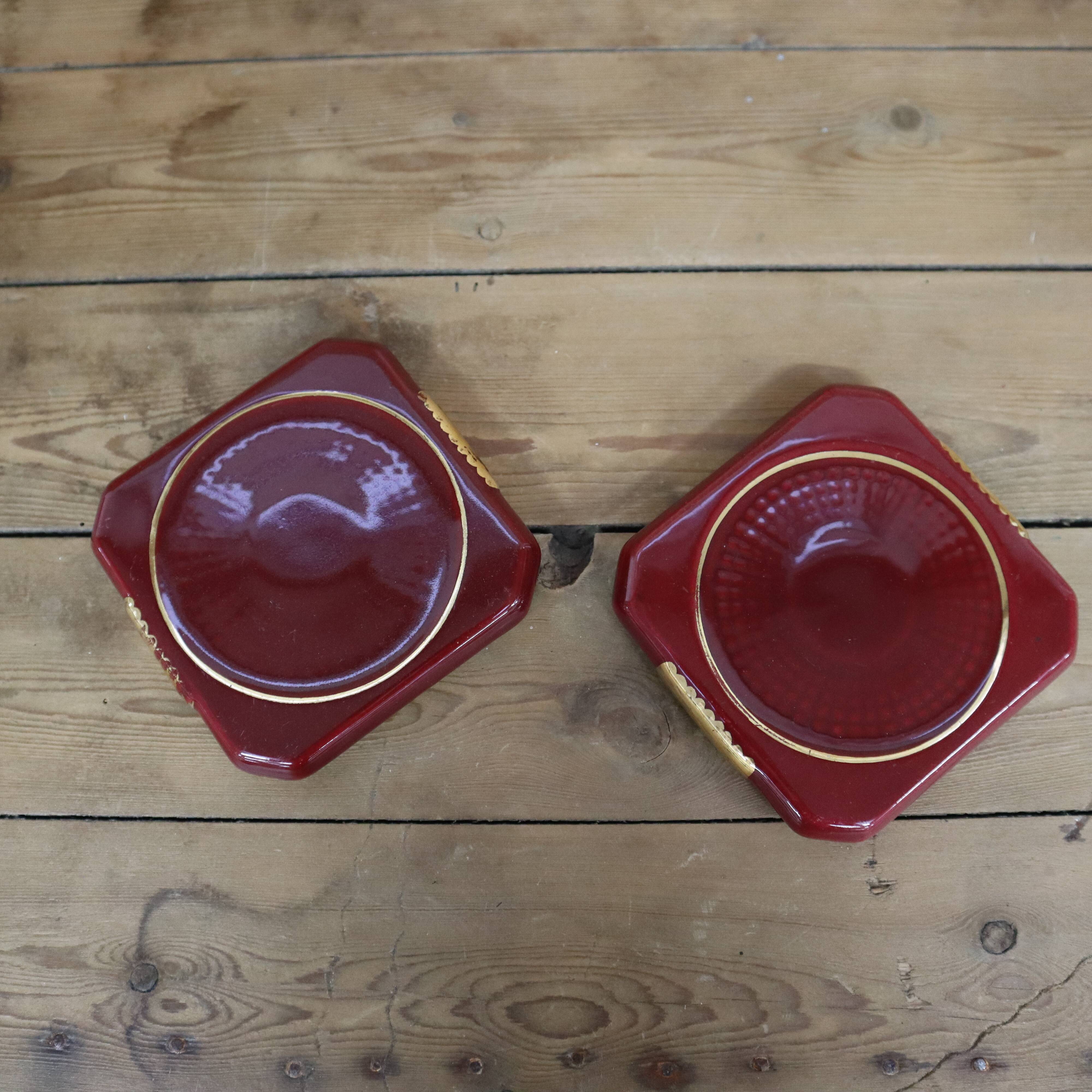 Pair of burgundy ceramic coasters or bottles with gold trim