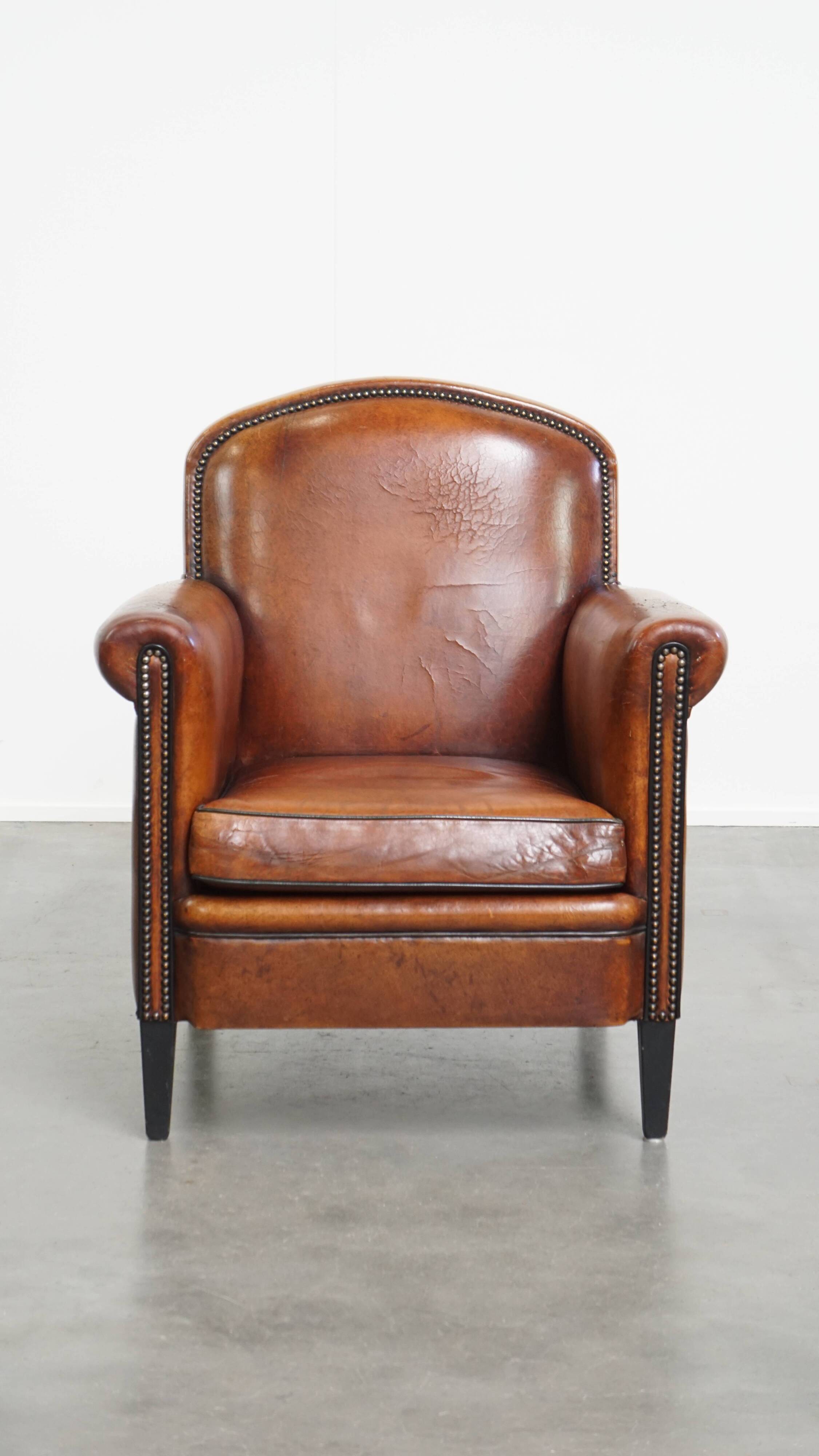 Sheepskin leather armchair in a cognac color with black piping