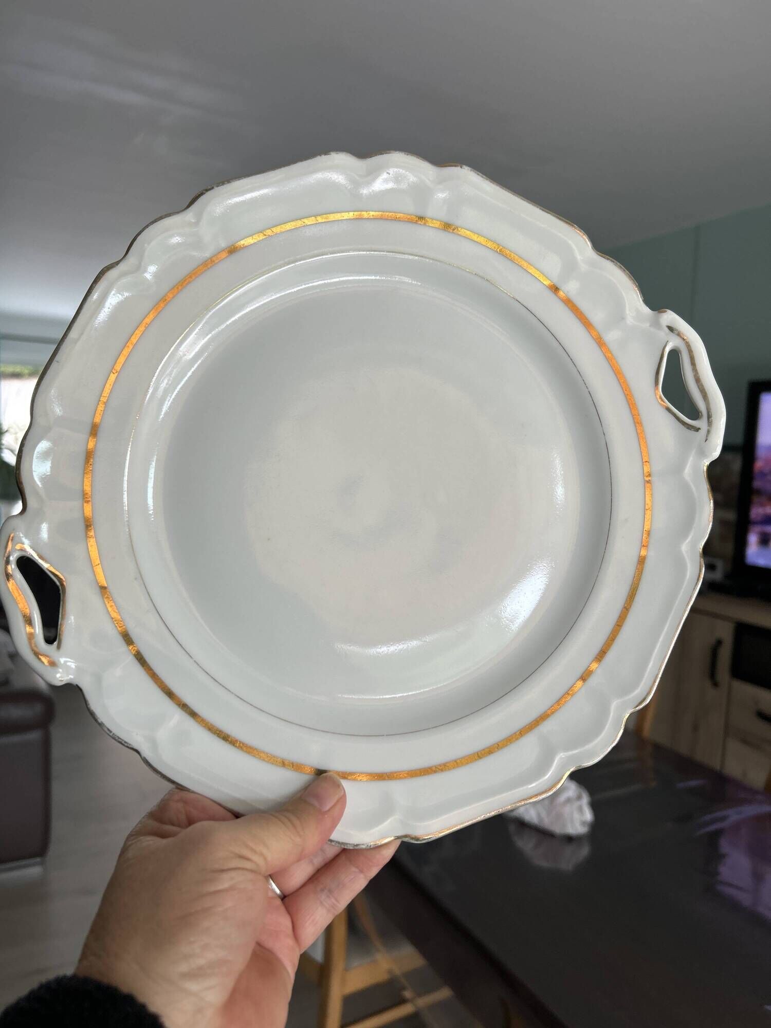 This dish seems to be a serving dish or a round plate with handles in porcelain.