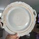 This dish seems to be a serving dish or a round plate with handles in porcelain.