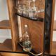 Compact bar cabinet with a pivoting door in black wood.
