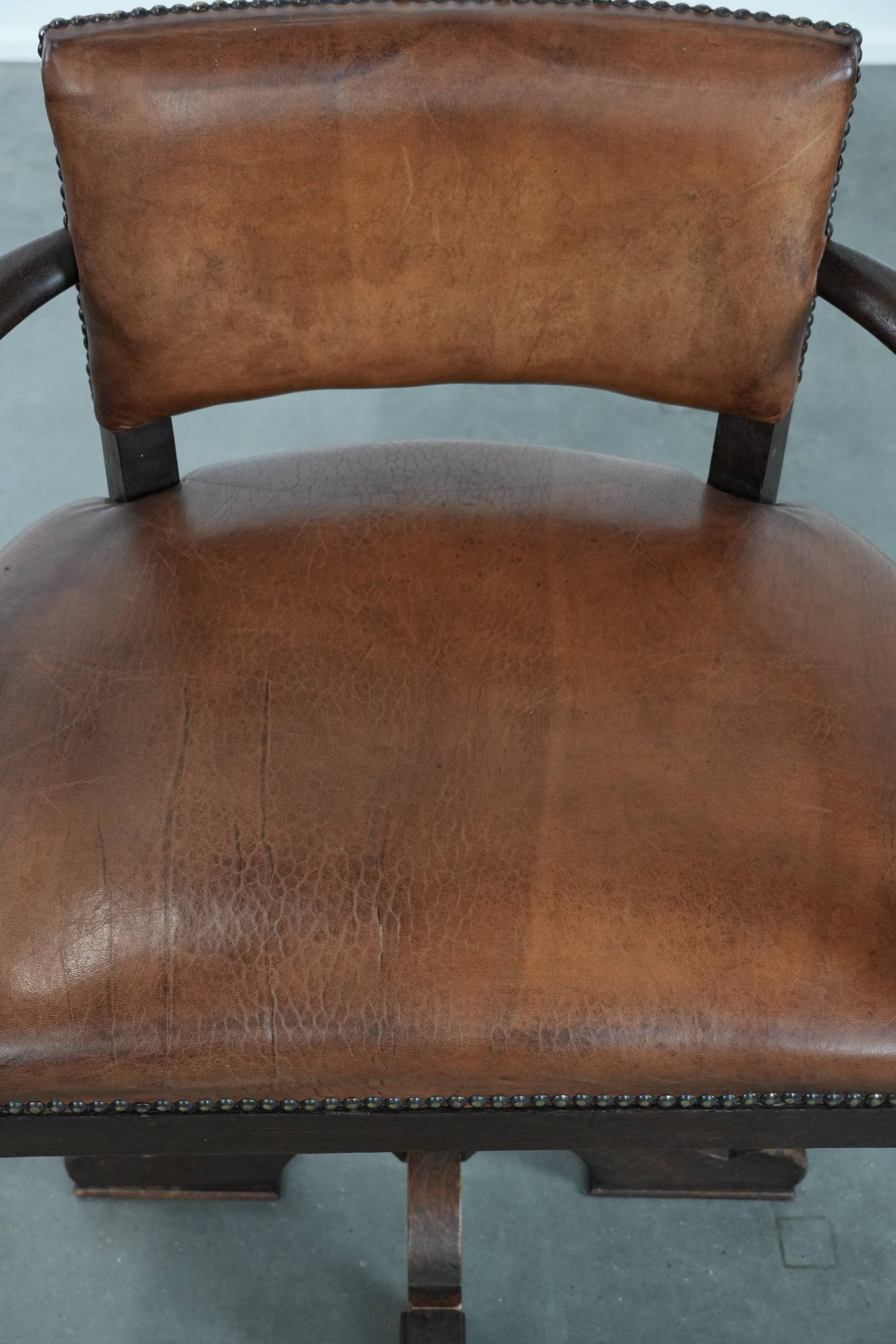 Elegant antique sheepskin leather desk chair with a heavy wooden frame
