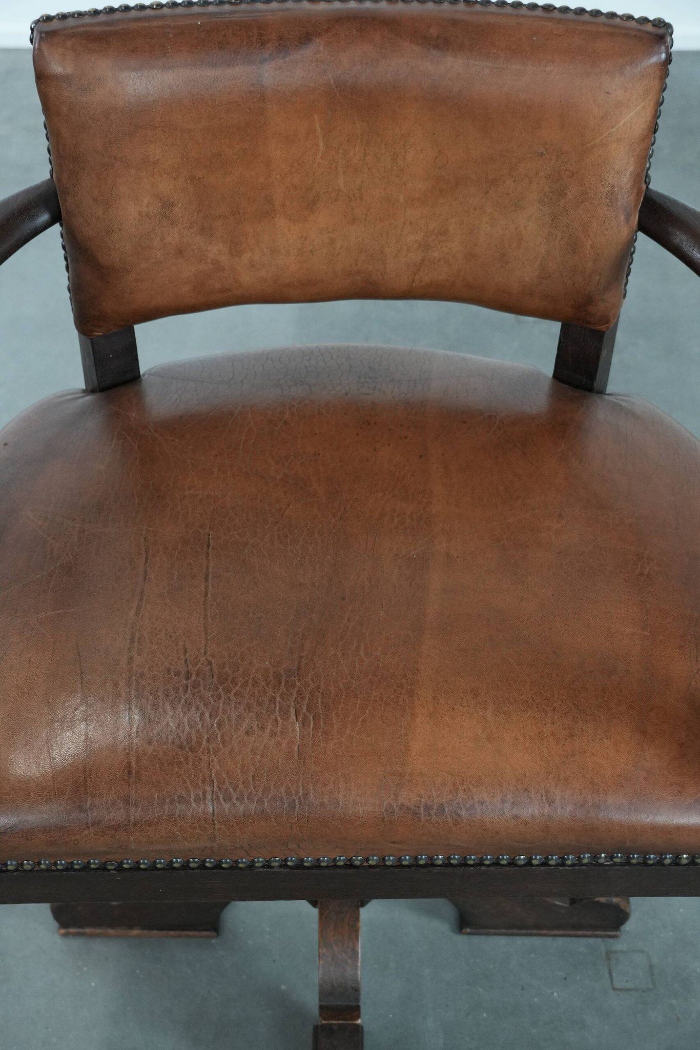 Elegant antique sheepskin leather desk chair with a heavy wooden frame