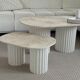 Oval coffee table duo travertine and white fluted wooden legs.