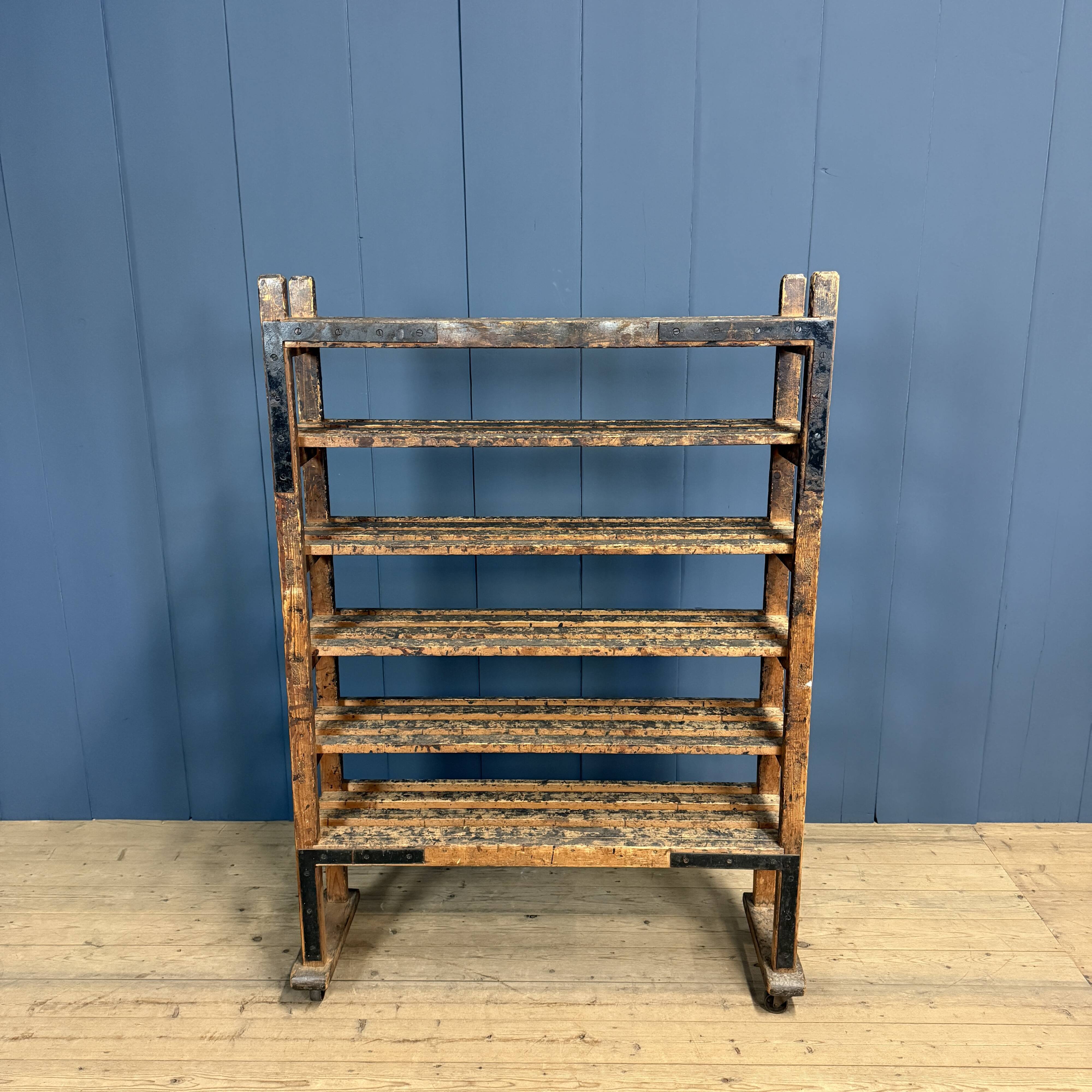 Old wooden workshop shelf with cast iron wheels.