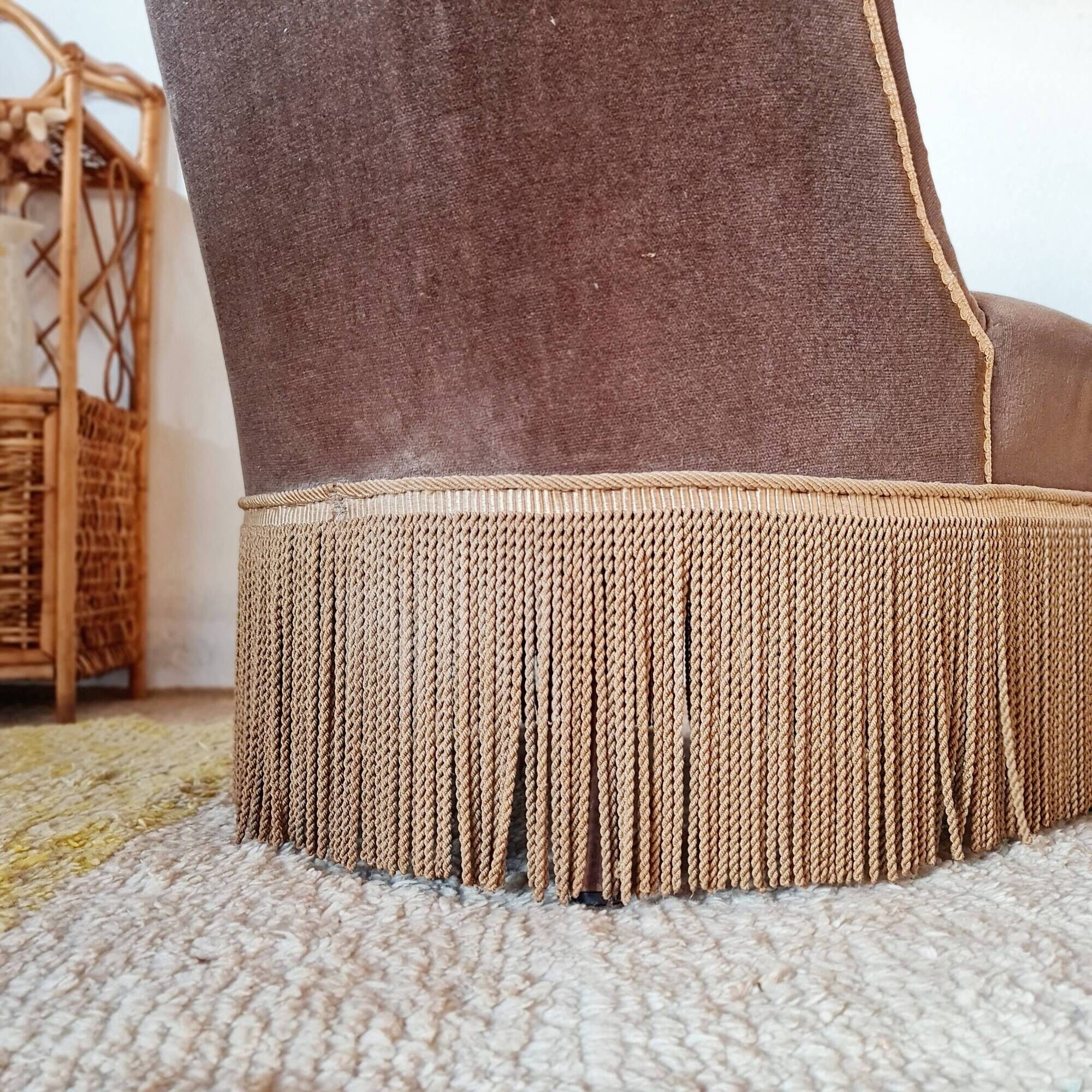 Brown velvet crapaud armchair with fringes and sculpted legs.