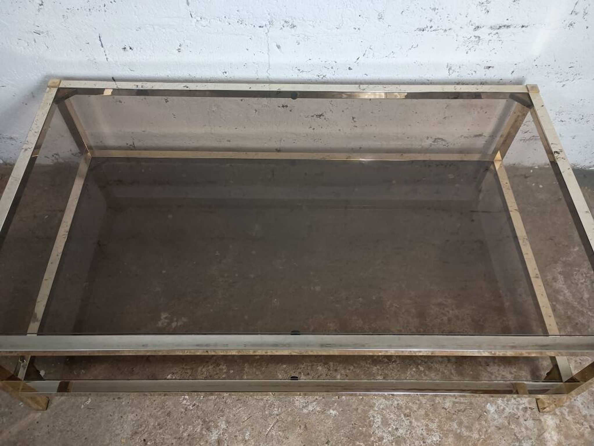 1970s coffee table in brass with a double smoked glass top.