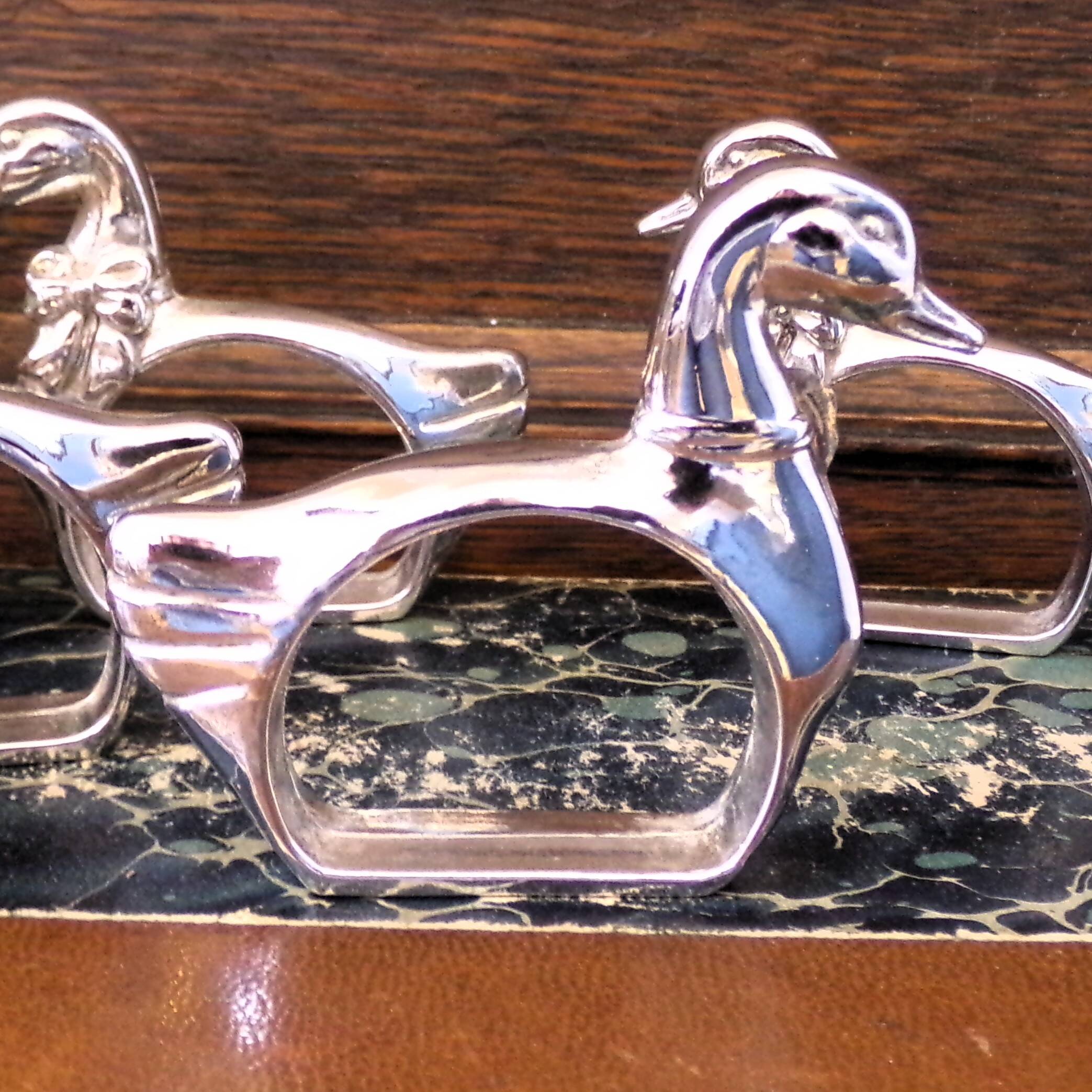 Four silver-plated napkin rings in the shape of a duck/goose