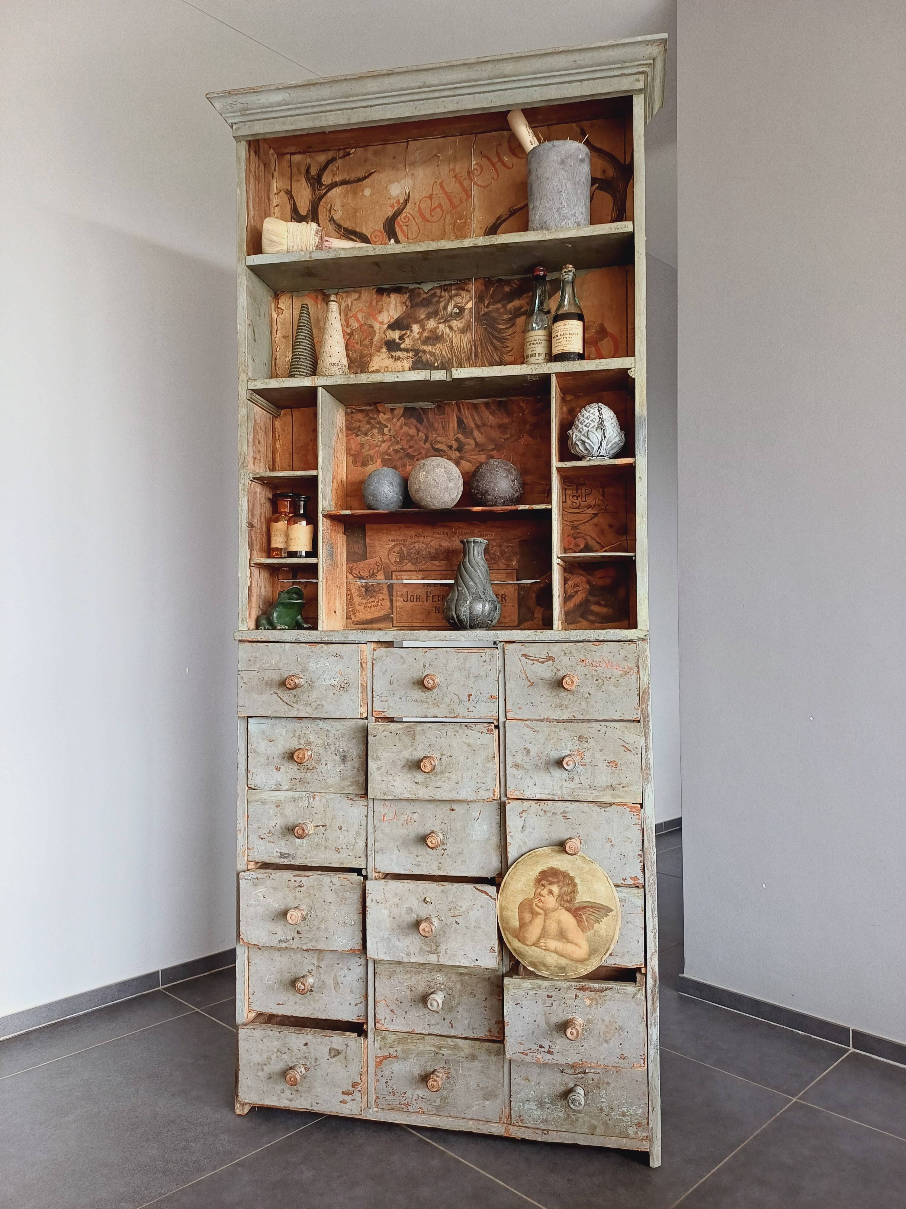 Craft cabinet with drawers with a very old tobacco advertisement in the background