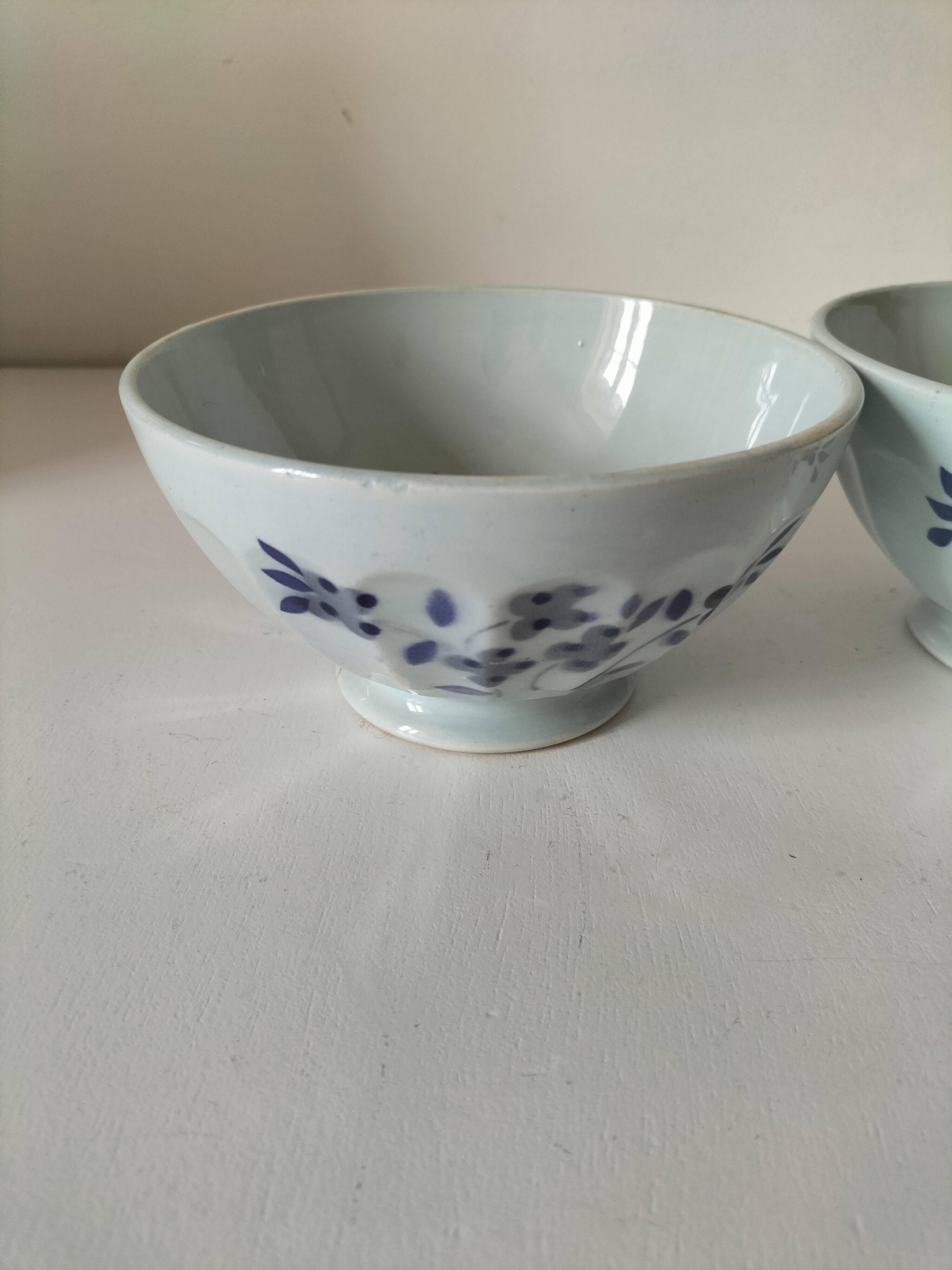 Two vintage farm bowls on a pale blue pedestal with floral decoration.