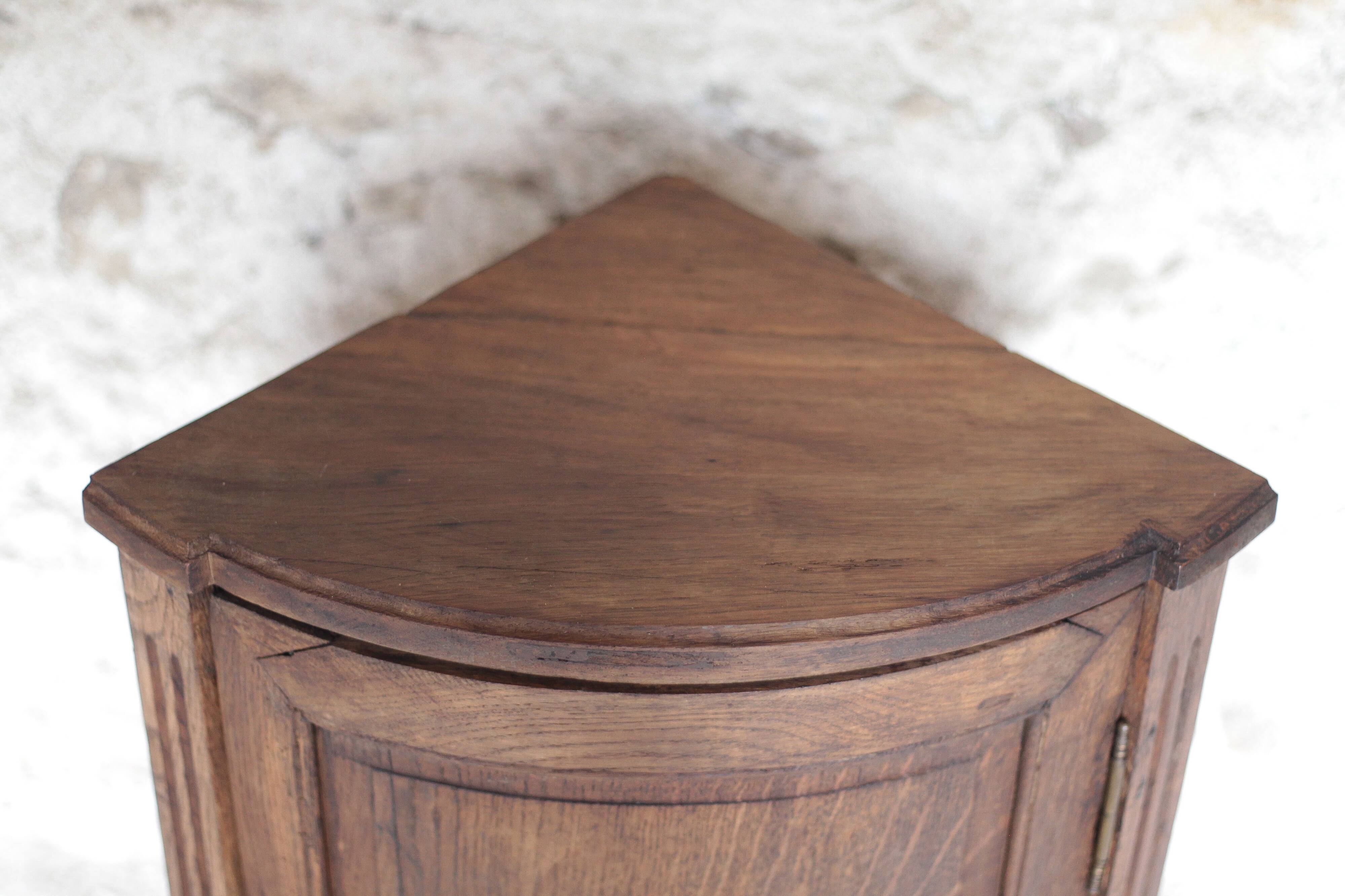 Antique wooden corner cabinet with a curved door.