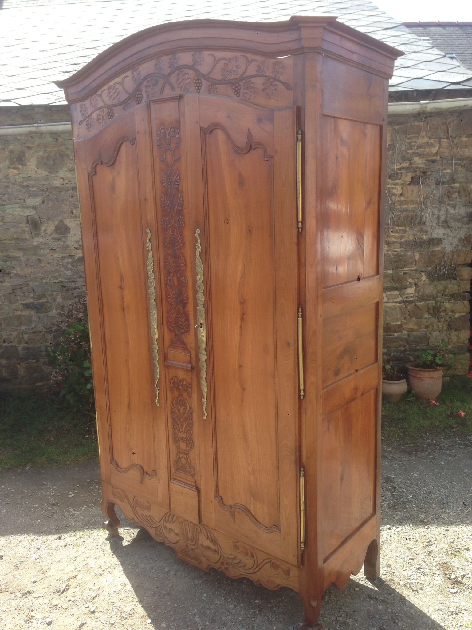 Armoire Louis XV Nantaise sculptée à grappes de raisin, chapeau de gendarme en cerisier fin 19eme.
