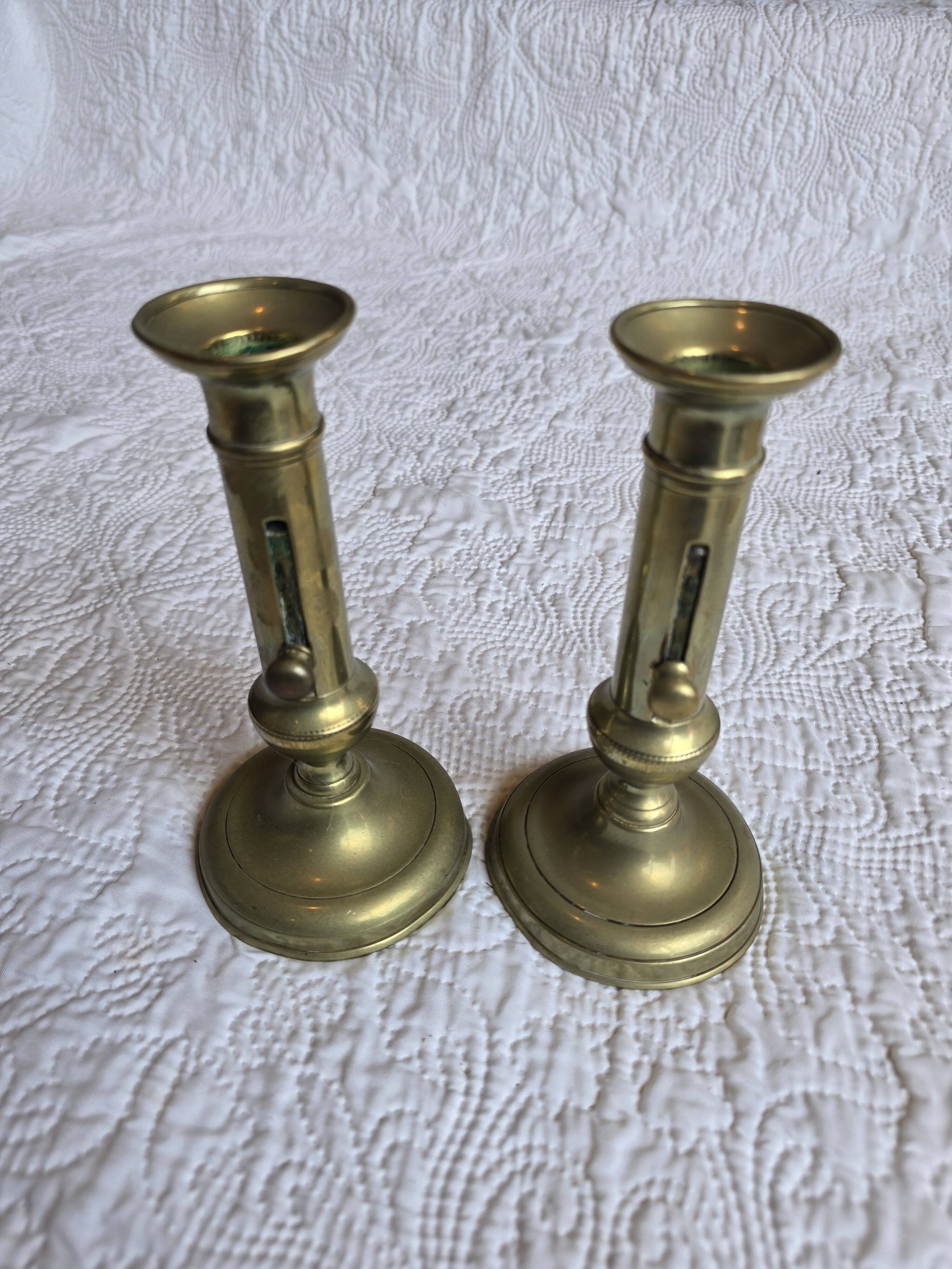 Pair of antique brass candlesticks with adjustable push mechanism from the 19th century.