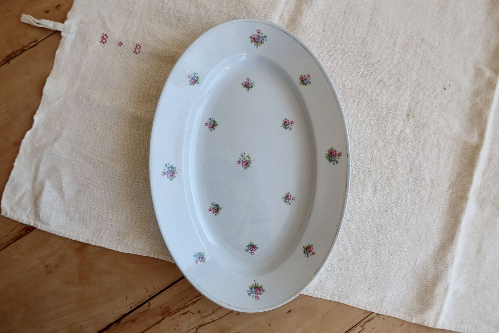 Antique oval serving dish in pale blue earthenware with a small flower design.