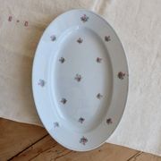 Antique oval serving dish in pale blue earthenware with a small flower design.