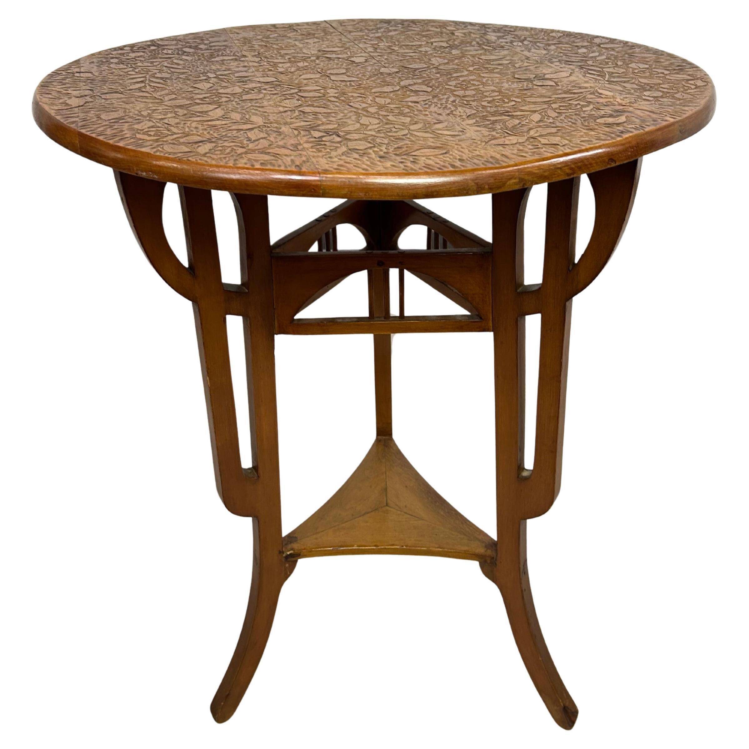 Round Art Nouveau coffee table with a sculpted top.