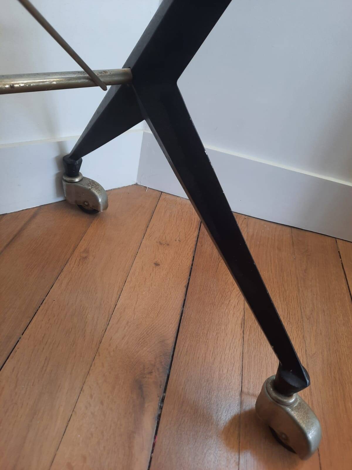 Vintage table with thick glass top and black steel legs with casters.