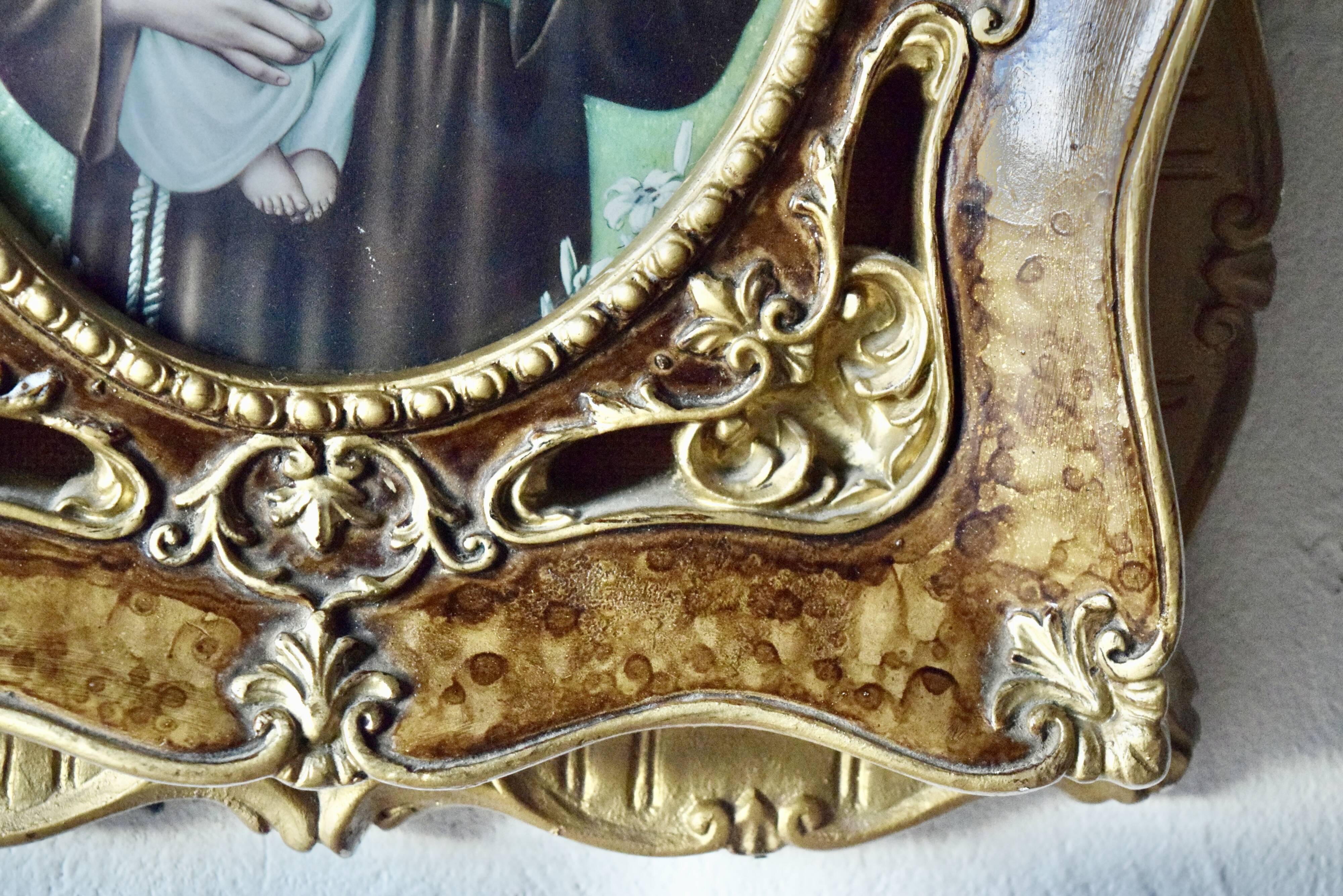 Old religious light frame in gilded stucco and curved glass