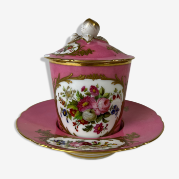 Pink cup accompanied by its saucer and lid