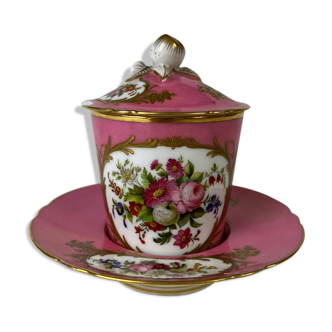 Pink cup accompanied by its saucer and lid