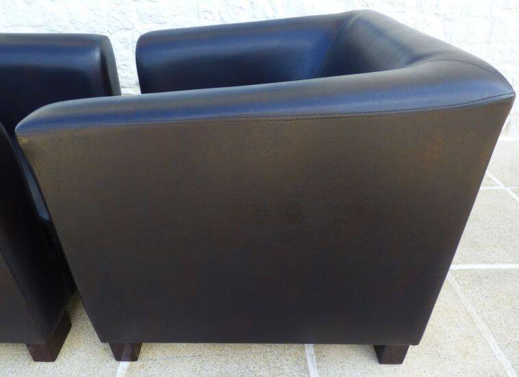 2 club armchairs with a chocolate faux leather seat and backrest and wooden legs.