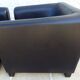 2 club armchairs with a chocolate faux leather seat and backrest and wooden legs.