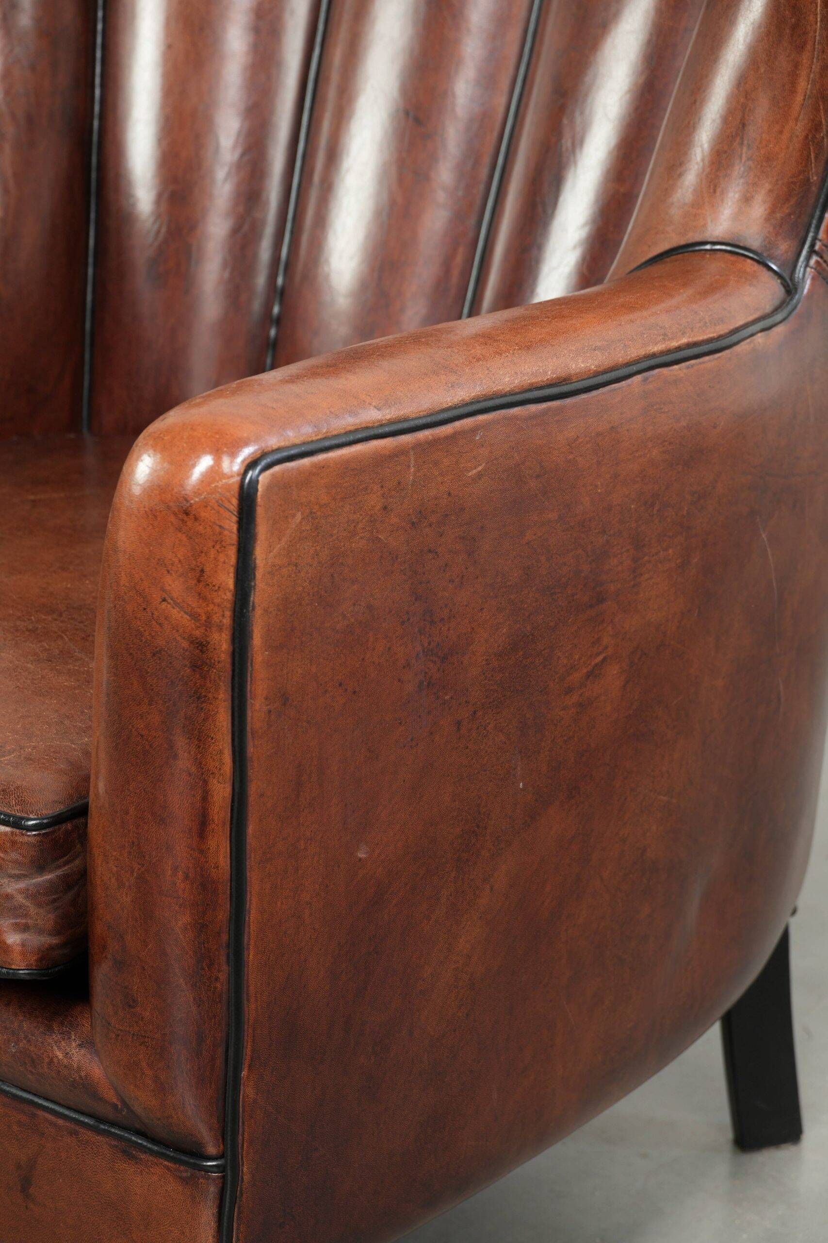 Fauteuil en peau de mouton confortable au design unique, fini avec un passepoil noir.