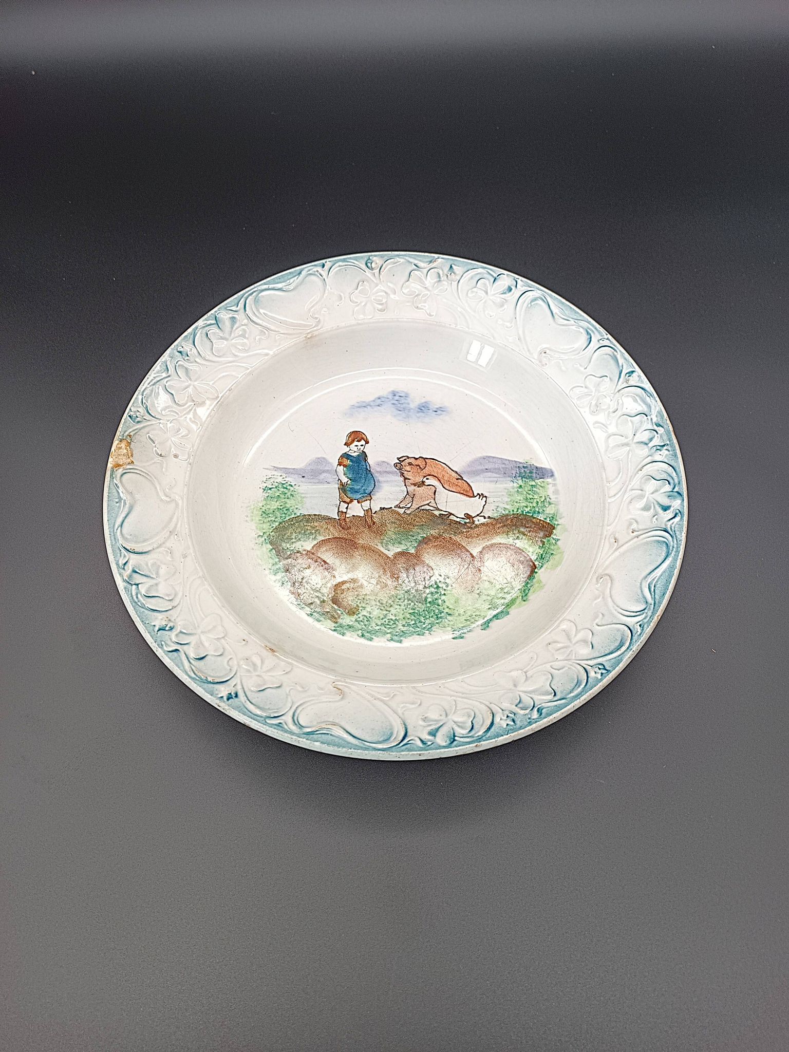 Large antique hollow dish from the 19th century, earthenware with pastoral decoration featuring a child, pig, and goose.