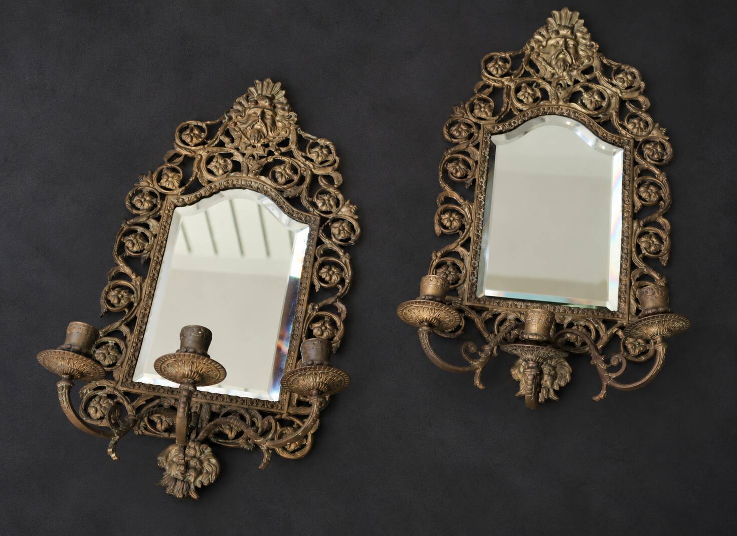 Pair of mirror wall sconces with brass candle holders.