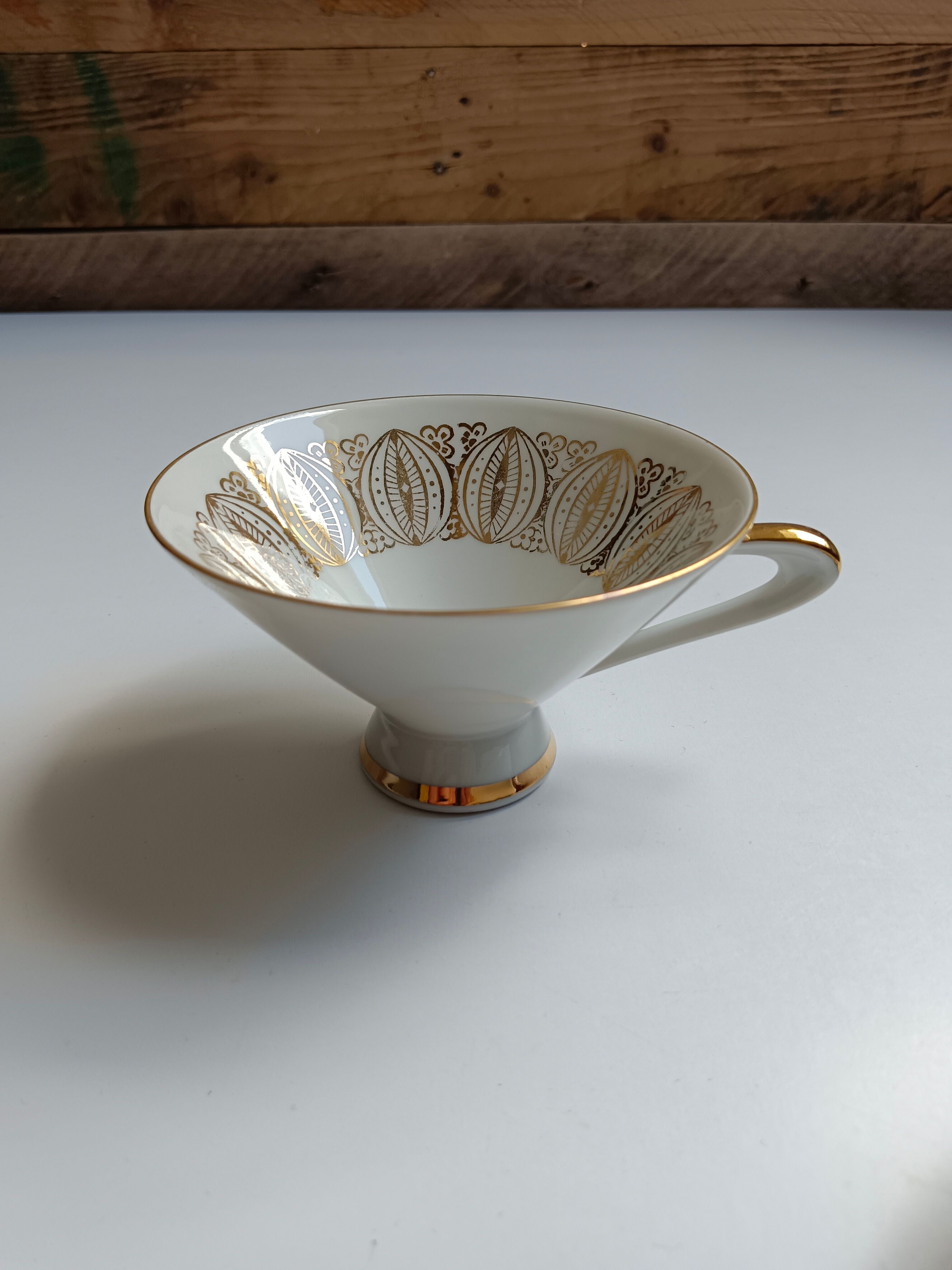 Solitaire tea cup, saucer, and dessert plate in white and gold.