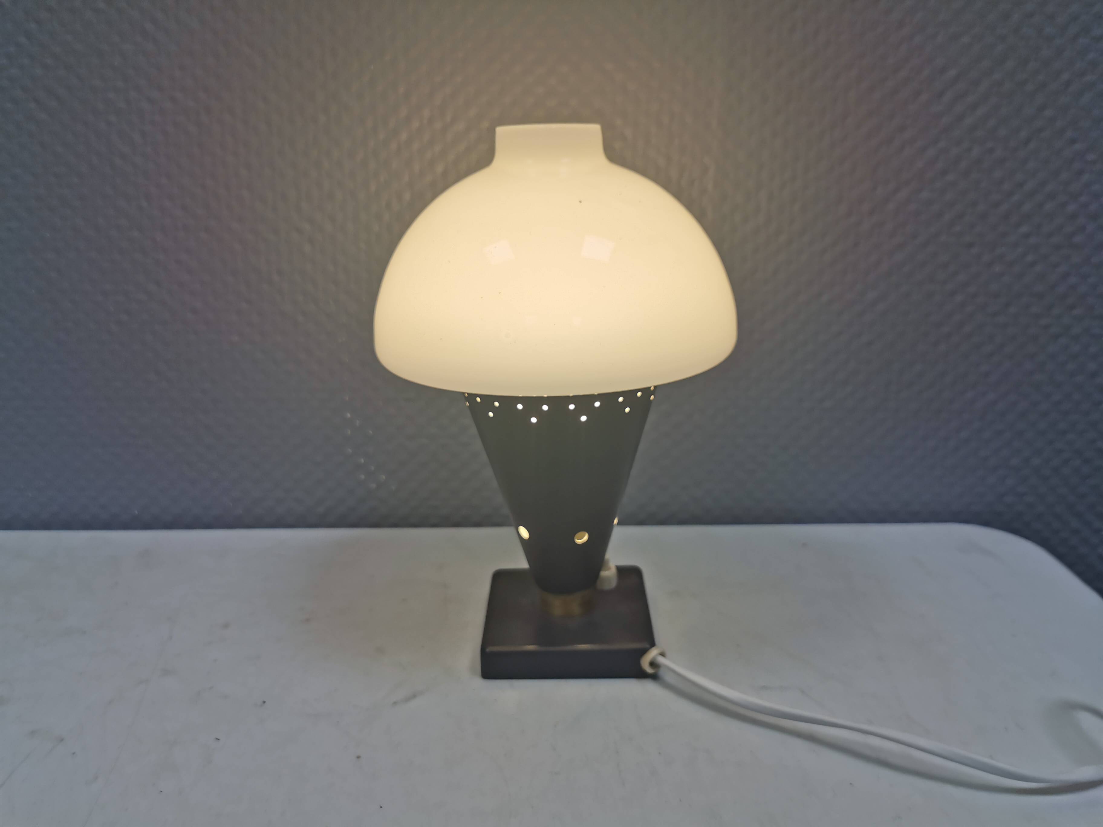 Small stylish table lamp with perforations and milky white opal glass shade