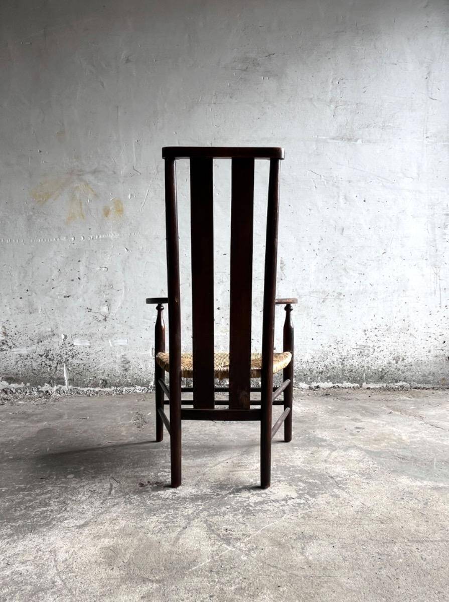 Dark brown solid wood Arts & Crafts armchair with natural rush seat and high back