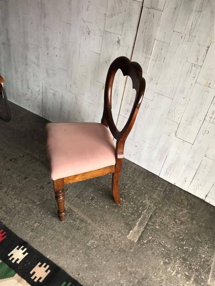 Fauteuil ancien en tissu rose et bois, dossier ajouré en cœur, pieds tournés